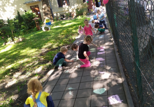 Dzieci rysują kredą po chodniku