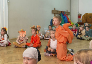 Dzieci z jesiennych strojach siedzą na podłodze