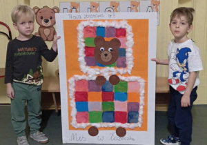 Chłopcy prezentują pracę plastyczną "Miś w łóżeczku" wykonaną prze całą grupę