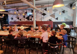 dzieci z grupy IV jedzą pizzę