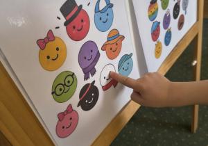 Dziecko wskazuje na tablicy białą kropkę z czerwonym szalikiem